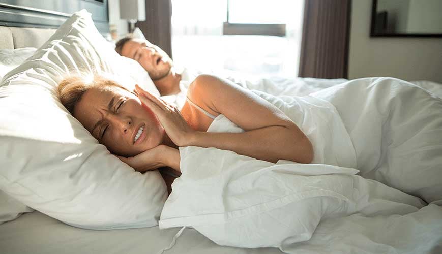 Women covering ears because her husband is snoring