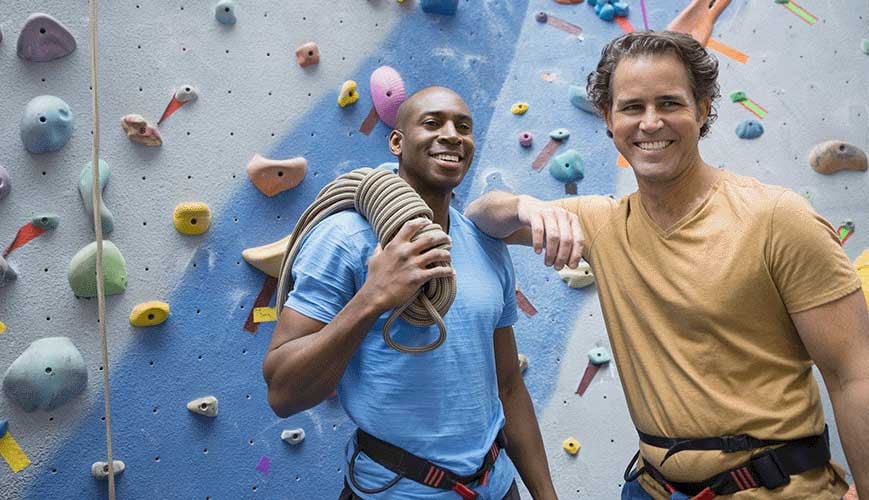 Male Friends Rock Climbing in Gym