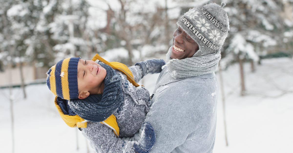 A father and son enjoying the snow reminding everyone of common winter injuries and how to avoid injury when shoveling snow.